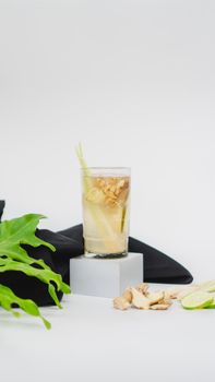 A vertical shot of a healthy ginger and lemongrass cold drink with lime on a white background.