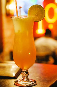 Chilled orange cocktail with a lime slice garnish on a Parisian bar table.