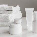 Minimalist arrangement of white skincare products and towels for a modern aesthetic.