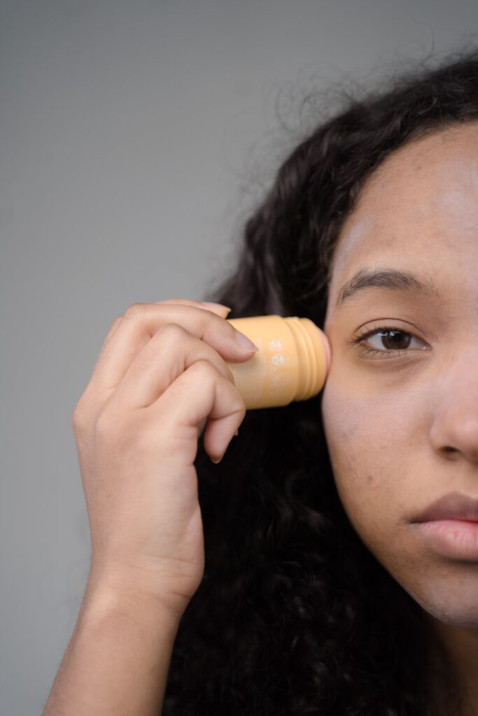 A woman applies skincare in a close-up half-face view, emphasizing self-care.